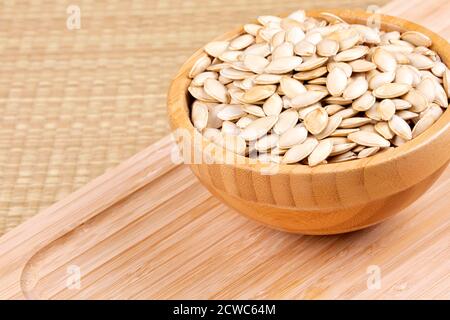 Schüssel voll mit leckeren Kürbiskernen, ein gesunder Snack auf einem hölzernen Hintergrund Stockfoto