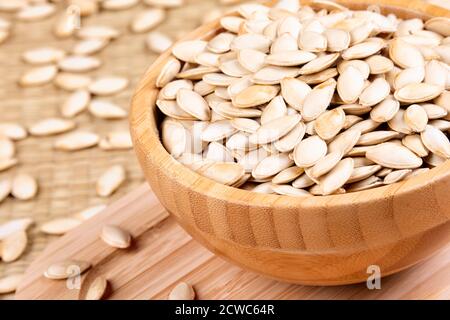 Schüssel voll mit leckeren Kürbiskernen, ein gesunder Snack auf einem hölzernen Hintergrund Stockfoto