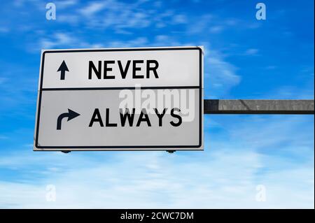 Nie und immer Straßenschild auf blauem Himmel Hintergrund. Weiße zwei Straßenschilder mit Pfeil auf Metallmast. Richtungsstraße, Wegzeichen Kreuzung, zwei Pfeil Stockfoto