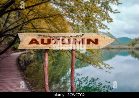 Herbst Holzpfeilstraße Schild gegen See und Wald mit roten und gelben Bäumen. Stockfoto