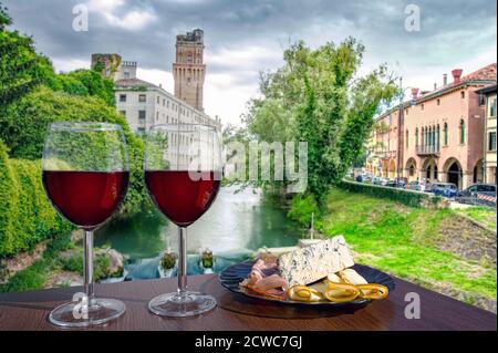 Zwei Gläser Rotwein mit Käse und Fleischsnacks mit Blick auf den Kanal in Italien. Stockfoto