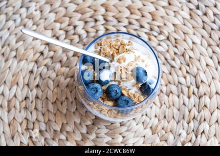 Gesundes und leckeres Frühstück. Granola Parfait mit Joghurt und Heidelbeeren mit Ahornsirup Stockfoto
