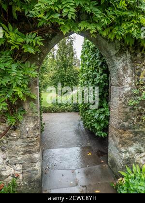 Blick durch einen steinernen Torbogen in den Garten auf einem Nasser Herbsttag Stockfoto