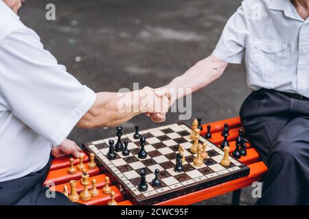 Zwei ältere Erwachsene Männer spielen Schach auf der Bank im Freien Im Park Stockfoto