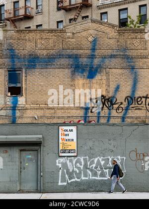 Brooklyn, New York City - 22. Mai 2016: Mann, der an alten Gebäuden in Borinquen Place, Brooklyn, New York, vorbei läuft. Stockfoto