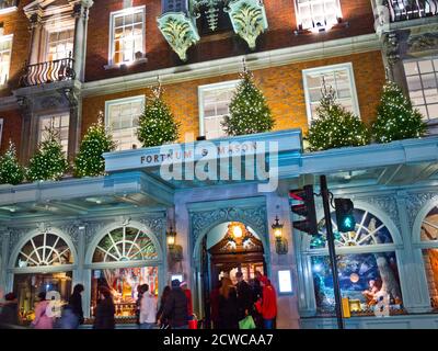 Fortnum & Mason Department Store beschäftigt an Weihnachten mit Shopper, Fassade mit beleuchteten Weihnachtsbäumen Piccadilly London UK dekoriert Stockfoto