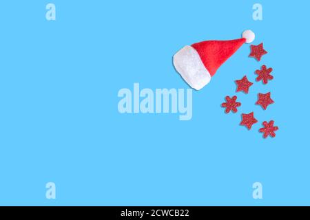 Weihnachtsmann Hut mit roten Sternen und Schneeflocken isoliert auf blauem Hintergrund. Kleine Weihnachtsmütze mit Kopierplatz. Mockup für Weihnachten, Silvester feiern Stockfoto