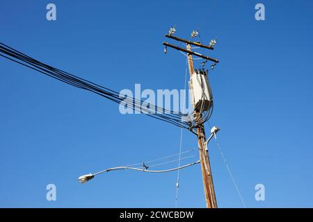 Pfosten/Lampenpfosten und Drähte gegen einen blauen Himmel Stockfoto