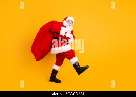 Volle Länge Körpergröße Profil Seitenansicht seiner HE Nette lustige fröhliche erstaunt weißhaarige Santa trägt großen großen Sack Benutzerdefinierte Tradition isoliert hell Stockfoto