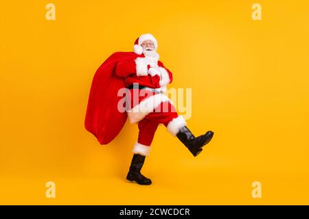 Volle Länge Körpergröße Profil Seitenansicht seiner HE Nette lustige fröhlich weißhaarige Santa St. Nicholas gehen große tragen Großer Sack Verkaufsladen isoliert Stockfoto