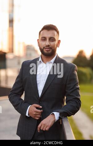 Porträt des jungen bärtigen Geschäftsmann in schwarzem Anzug Blick auf Kamera im Freien Stockfoto