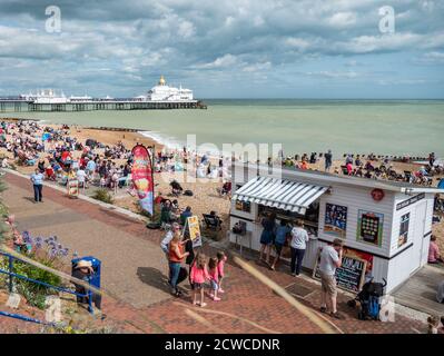 Eastbourne Seafront, England. Eine geschäftige Strandszene auf dem Höhepunkt des englischen Sommers mit Touristen, die das warme Wetter an der britischen Südküste genießen. Stockfoto