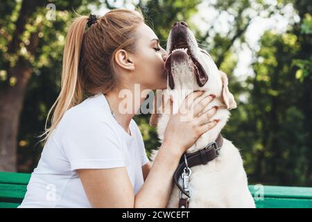 Nahaufnahme einer kaukasischen Frau, die ihren labrador küsst Während eines Sommerspaziergangs im Park Stockfoto