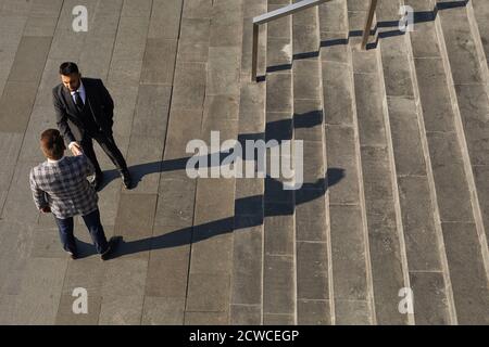 High-Angle-Ansicht von zwei Geschäftsleuten schüttelt die Hände Begrüßung jeder Andere während des Treffens in der Stadt Stockfoto