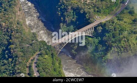 Luftaufnahme der berühmten Victoria Falls Bridge, die die Grenze von Simbabwe und Sambia (Afrika) markiert, über Sambesi Fluss mit dem Spray der Wasserfälle. Stockfoto