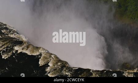 Nahaufnahme Luftaufnahme in der Kehle der majestätischen und mächtigen Victoria Falls mit enormem Wasserstrahl am Ende der Regenzeit vom Hubschrauber. Stockfoto