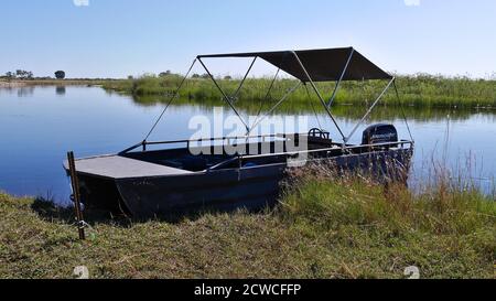 Bwabwata National Park, Namibia - 04/28/2018: Kleines Safariboot an einer Metallstange gebunden auf einer Insel im Kwando River, Caprivi Strip. Stockfoto