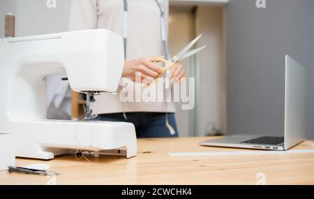 Dressmaker schneidet Schere Muster Kleid Detail auf Skizze Linien für Nähmaschine. Arbeitsplatz der Näherin Stockfoto