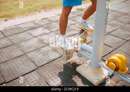 Nahaufnahme eines hübschen kaukasischen männlichen Athleten, der auf einem Stepper im Fitnessstudio im Freien trainiert. Muskulöser Sportler im Freien. Stockfoto