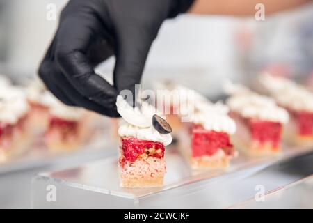 Chef Hand in Patisserie Restaurant bereitet Kuchen und dekoriert mit Schokoladeneisung Stockfoto