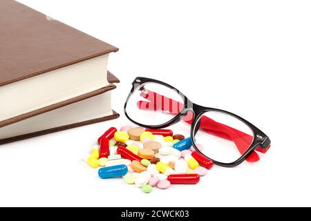 Stapel von Büchern und Pillen, Kapseln isoliert auf weißem Hintergrund. Arzneimittel. Medikamente und Medikamente. Stockfoto