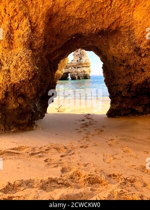 Einsamer Strand auf orangen Felsen Stockfoto