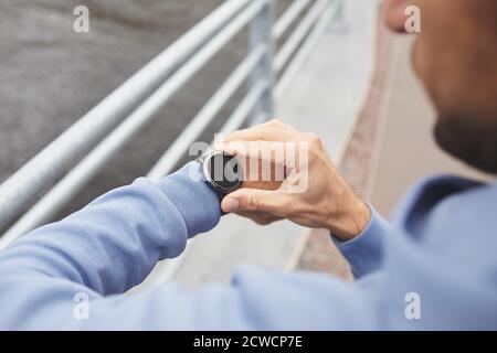 Nahaufnahme eines jungen Mannes, der die Zeit auf seiner Uhr beobachtet Im Freien stehen Stockfoto