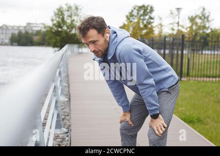 Junger Athlet atmet und ruht sich während des Sporttrainings aus Im Park Stockfoto