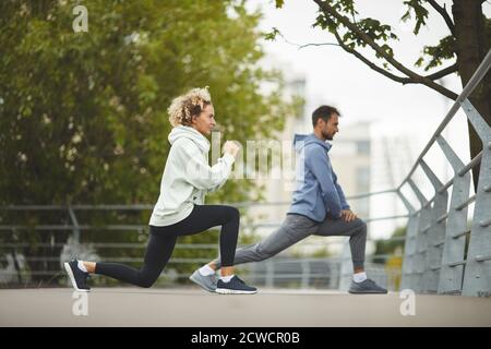 Junges Paar macht Übungen zusammen während des Sporttrainings in der parken Stockfoto