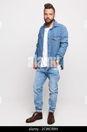 Junger Mann im Denim-Anzug. Schöner Mann in Jeansjacke und Jeans auf weißem Hintergrund. Foto für die Werbung Herren Jeans und Jacken. Konzept für Stockfoto