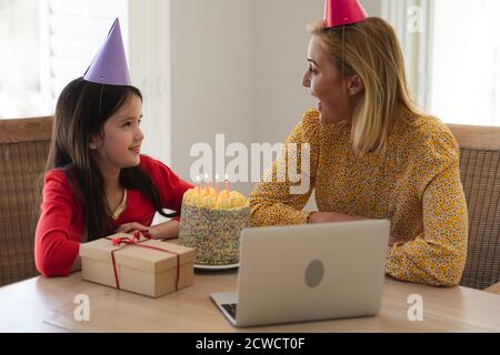 Kaukasische Frau und ihre Tochter verbringen Zeit zu Hause zusammen, Geburtstag feiern, mit einem Laptop-Computer, einen Videoanruf. Soziale Distanzierung Stockfoto