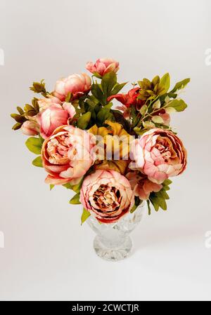 Ein Strauß von bunten Blumen in einer verzierten Kristallvase, vor einem hellen Hintergrund Stockfoto