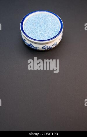 Vertikale Aufnahme von blauem Sand in einer porzellanschale auf Eine schwarze Oberfläche Stockfoto