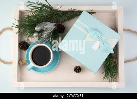 Weihnachtskomposition mit einer Geschenkbox, einer Tasse Kaffee, Weihnachtskugeln und einem Kiefernzweig auf einem weißen Tablett Stockfoto