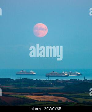 Abbotsbury, Dorset, Großbritannien. September 2020. Wetter in Großbritannien. Blick von Abbotsbury in Dorset auf den fast Vollmond, der über drei der leeren Kreuzfahrtschiffe in Weymouth Bay in den Himmel aufsteigt. Die Schiffe sind Cunards Queen Elizabeth, Queen Victoria und TUI's Marella Discovery. Dieser Mond, wenn er am 1. Oktober voll ist, wird der Erntemond genannt. Bild: Graham Hunt/Alamy Live News Stockfoto