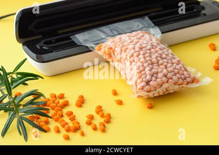 Kunststoffabdichtmaschine. Vakuumverpackung von frischen Sanddornbeeren. Langfristige Lagerung von Produkten. Selektiver Fokus. Stockfoto