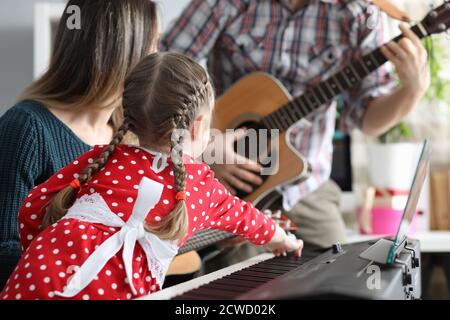 Tochter, Vater und Mutter spielen zusammen Musikinstrumente, Gitarre, Spionino Stockfoto