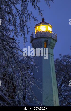 Leuchtfeuer des Port Sanilac Leuchtturms, umgeben von Eiszapfen in einer kalten Winternacht. Stockfoto