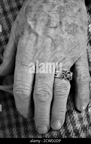 Nahaufnahme der alten Dame Hände geklammt zeigt Finger und Hochzeit und Verlobungsring mit faltigen weiblichen Fleisch und braun Altersflecken entspannt sitzen Stockfoto