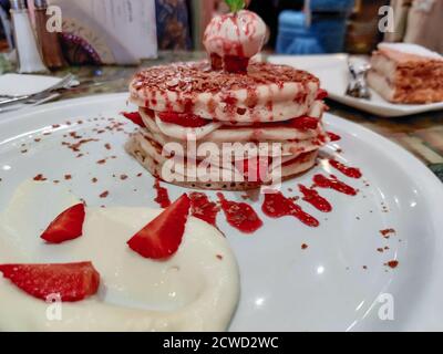 Nahaufnahme von Dessert in einem schicken Restaurant serviert Erdbeer- und Vanillepfannkuchen oben mit einer Eisportionierer Stockfoto