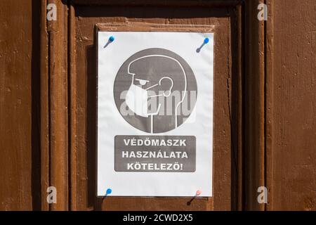 Vedomaszk hasznalata kotelezo (tragen Sie die Gesichtsmaske) Warnschild an der Eingangstür des Hauses, Sopron, Ungarn gefestt Stockfoto