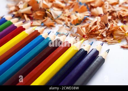 Buntstifte in verschiedenen Farben mit vielen Farbspänen. Nahaufnahme mit flachem Freiheitsgrad. Isoliert auf weißem Hintergrund. Stockfoto