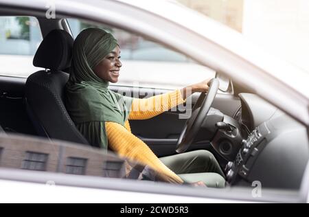 Probefahrt. Black Muslim Lady Fahren Auto In Der Stadt, Check New Auto Stockfoto