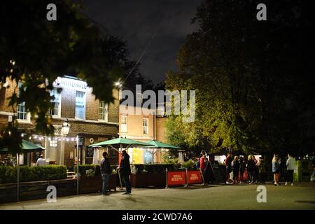 Die Menschen bereiten sich darauf vor, die Windmühle in Clapham Common in London um 21:55 Uhr zu verlassen, nachdem in England eine Reihe neuer Beschränkungen gegen den Anstieg der Coronavirus-Fälle in Kraft traten. Stockfoto