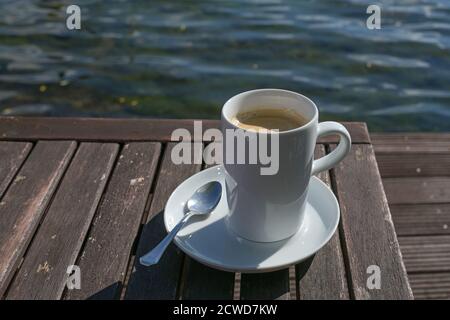 Große Tasse mit Kaffee auf einem Holztisch direkt am Wasser in einem Outdoor-Café, Kopierraum, ausgewählter Fokus, enge Schärfentiefe Stockfoto