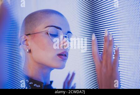 Bild einer schönen jungen Frau posiert gegen eine LED-Panel. Rasierte Kopf Teenager mit alternativen Look machen urbane Porträts Stockfoto