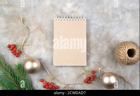 Weihnachtskomposition von Notepad, Weihnachtsspielzeug, Retro-Kamera und rotem Viburnum auf grauem Hintergrund. Stockfoto