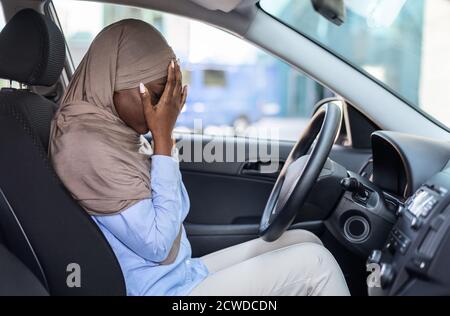 Gestresste schwarze muslimische Frau Fahrer im Auto sitzen, Gesicht mit Händen zu bedecken Stockfoto