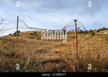 Metallzaun vor dem Trockenfeld im Spätsommer. Landschaft von Castilla la Mancha, Spanien Stockfoto