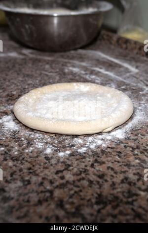 Pizzateig auf bemehlter Schieferfläche ausrollen, oben fotografiert Stockfoto